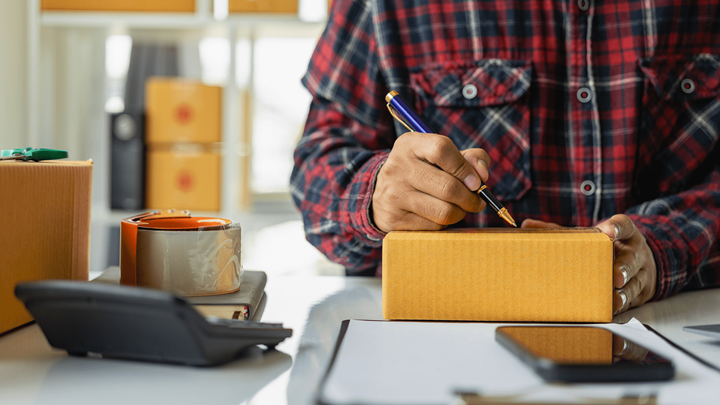 Someone labeling a package on a desk.