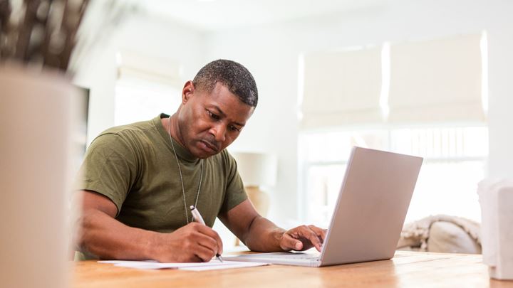 Veteran business owner filling out paperwork in front of a computer