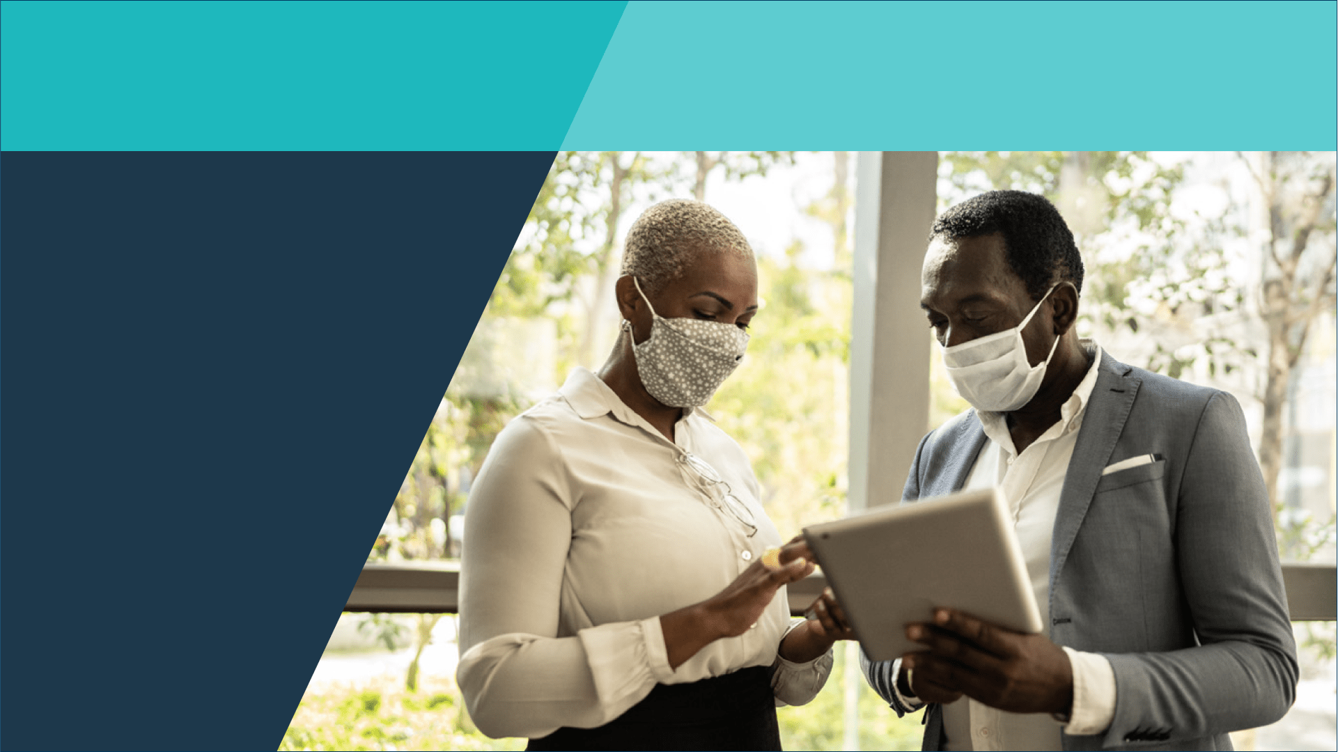 Two black individuals looking at an Ipad while wearing medical masks